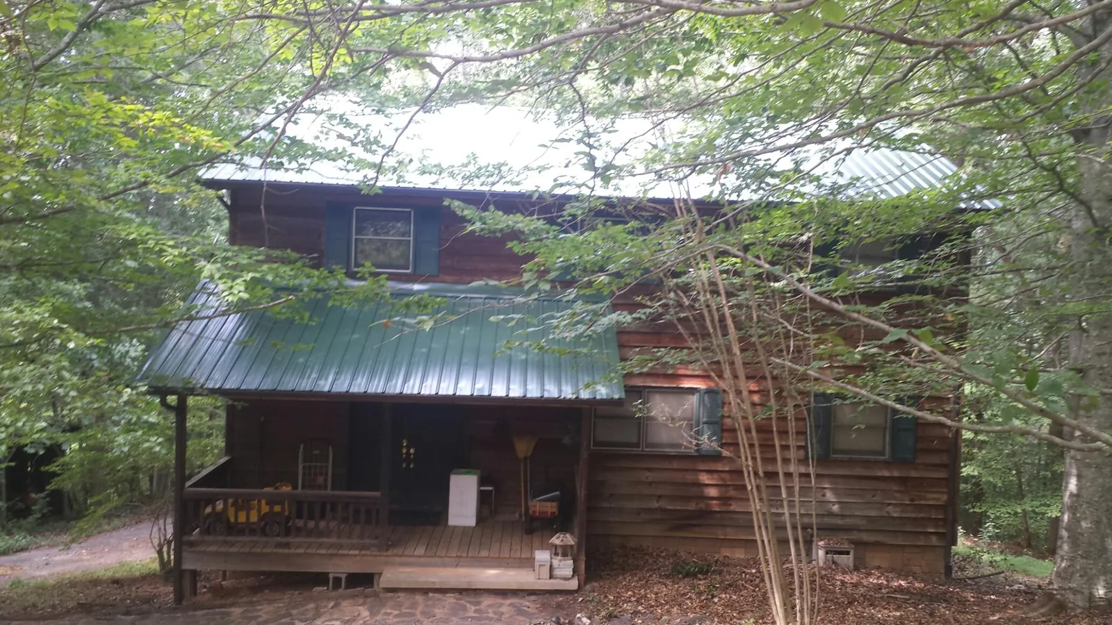 Green metal roof and covered porch on a log cabin in Fuquay Varina