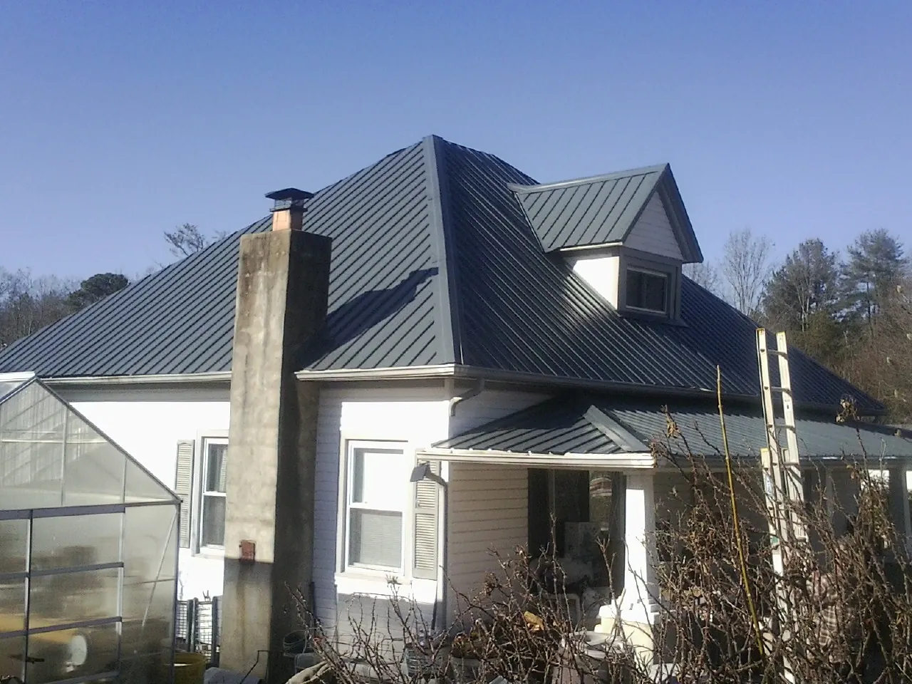 Dark blue standing seam metal roof on a white farmhouse with dormer — Slate & Tile Roof Repair by Roofing Brothers in Fuquay Varina