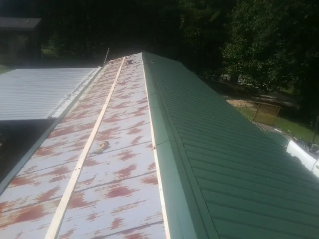 Old rusted panels beside newly installed green metal roofing — Wind Damage Roof Repair by Roofing Brothers in Fuquay Varina