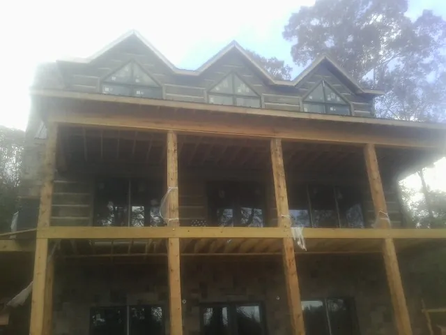 Dormers and porch framing on a large log home under construction — Roof Coating work by our crew in Fuquay Varina
