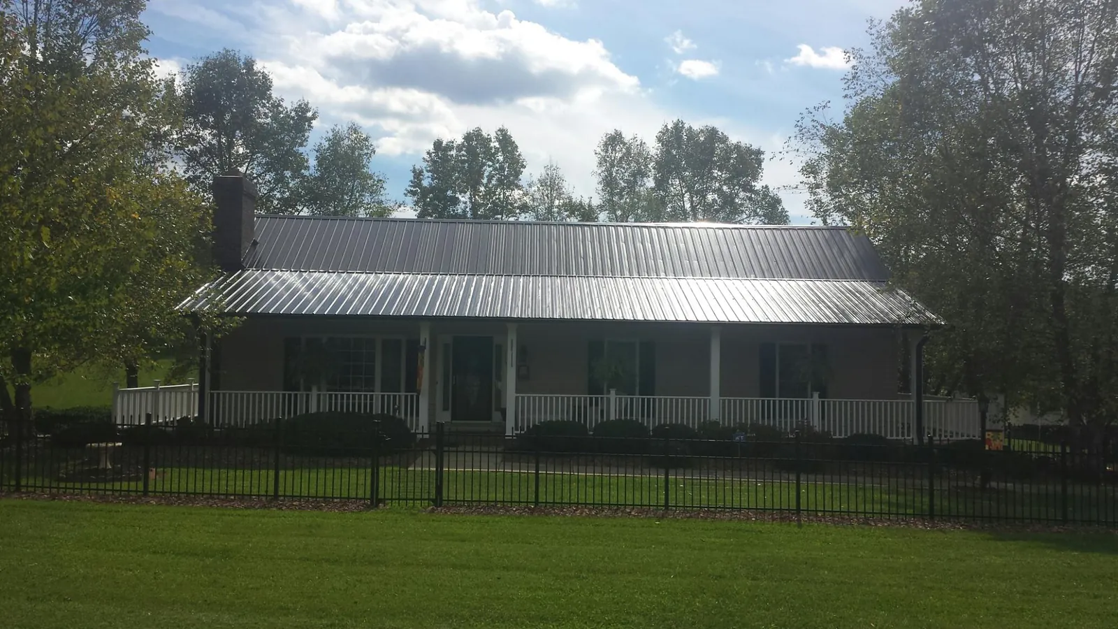 Gray metal roof on a brick ranch with a full width front porch — Gutter Guard Installation work by our crew in Fuquay Varina