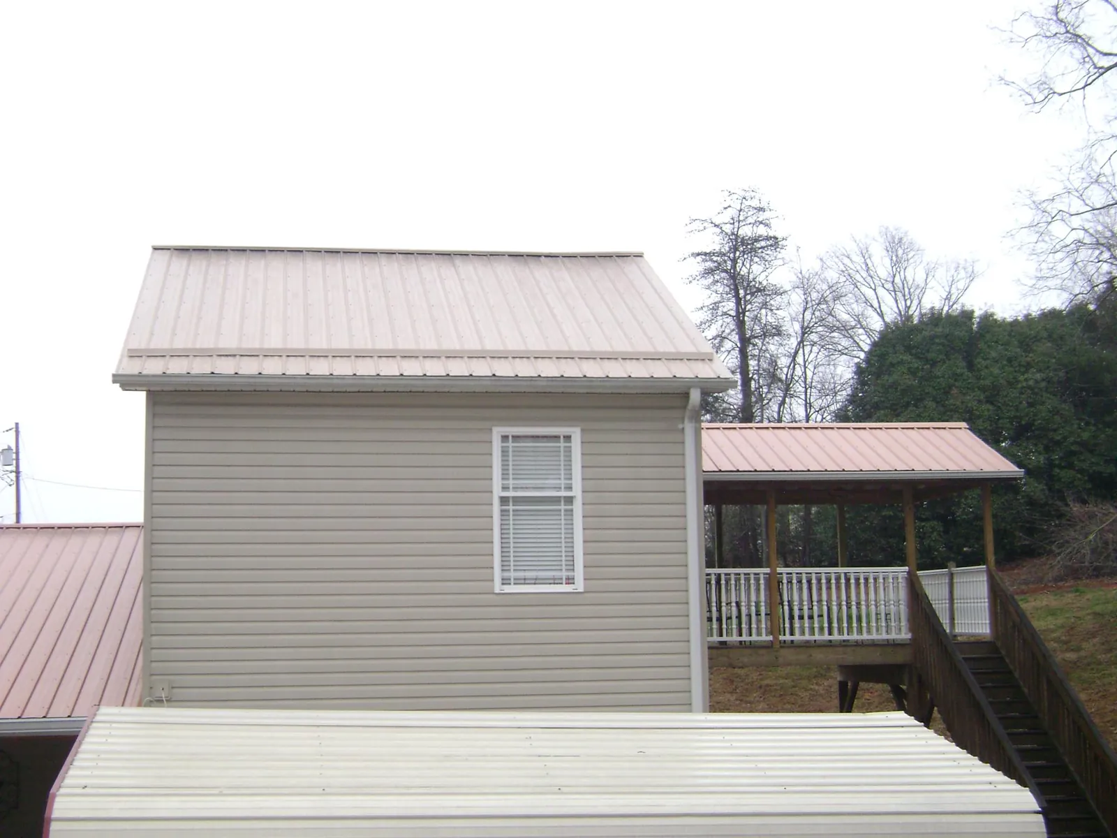 Tan metal roofs on a two story addition and attached porch, from a Roof Replacement job in Fuquay Varina
