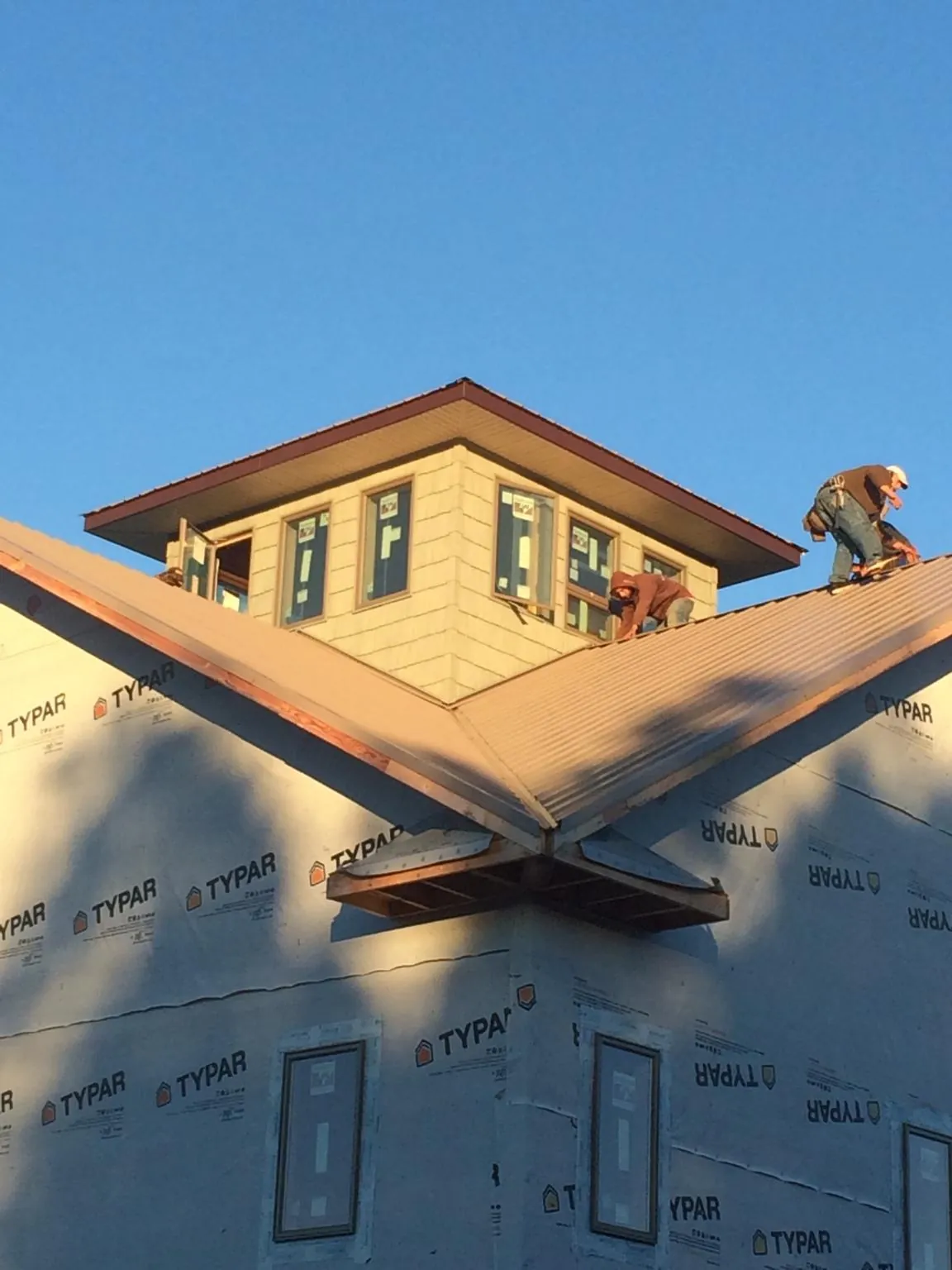 Roofers working around a rooftop cupola on a new metal roof at sunset — Roof Waterproofing in Fuquay Varina by Roofing Brothers